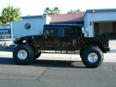 1982 Ford Bronco - A black Hummer H1 is parked on a residential street, oversized tires and company branding on its side.