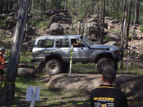 1982 Ford Bronco - A silver off-road SUV tackles a challenging rocky course during an event.