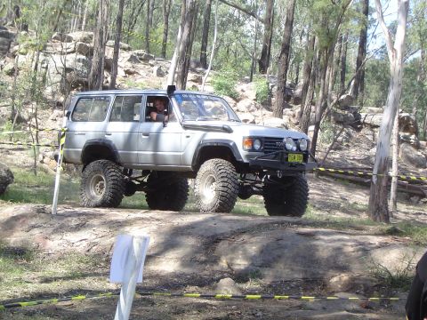 1982 Ford Bronco - This heavily modified SUV, likely a Toyota Land Cruiser from the 1980s, tackles an off-road course with its impressive suspension and tire…