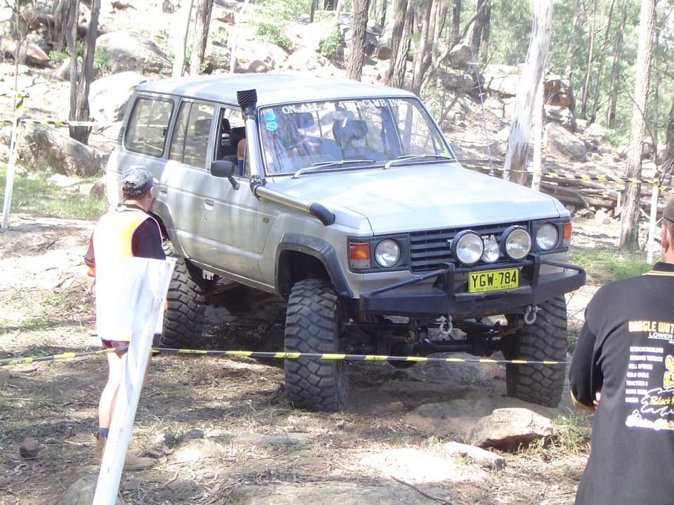 Silver Toyota Land Cruiser with snorkel and off-road tires navigating rocky terrain