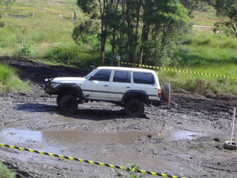 1982 Ford Bronco - White SUV navigating a muddy obstacle on an off-road course.