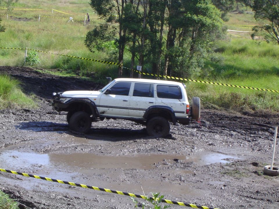 White SUV with spare tire on back stuck in mud on an off-road course