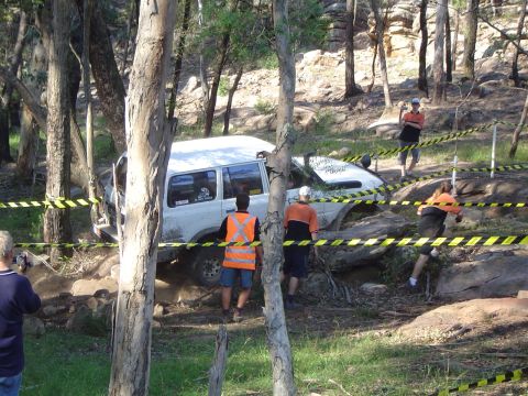 1982 Ford Bronco - A white SUV is stuck in a challenging off-road course, surrounded by trees and rocks.