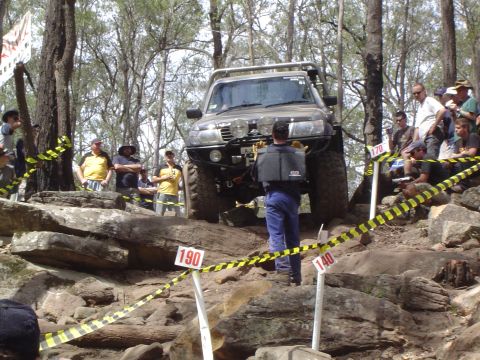 1982 Ford Bronco - Spectators watch an off-road vehicle tackle a challenging rocky course during an event.
