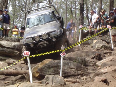 1982 Ford Bronco - A modified 4x4 navigates a challenging obstacle course with numbered markers and onlookers.