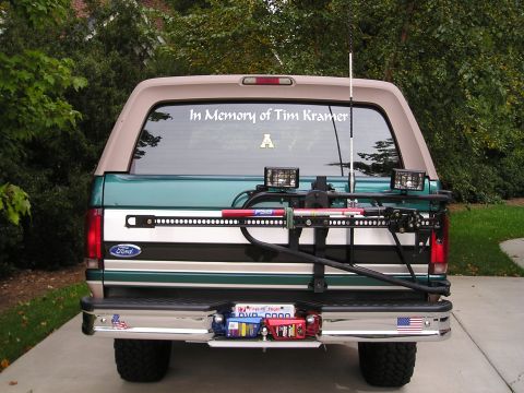 1996 Ford Bronco - Rear view of a 1996 Ford Bronco, a hi-lift jack mounted to the spare tire carrier and a memorial decal on the rear window.