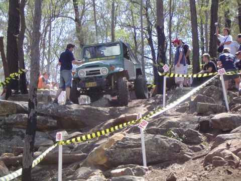 1982 Ford Bronco - A Toyota Land Cruiser FJ40 tackles a challenging off-road course with spectators watching.