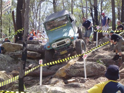 1982 Ford Bronco - A green off-road vehicle tackles a challenging rocky terrain during an event.