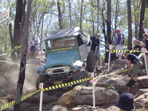 1982 Ford Bronco - A green off-road vehicle navigates a rocky course with a participant changing a tire.
