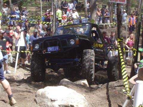 1982 Ford Bronco - An off-road vehicle tackles a challenging course with spectators observing the action.