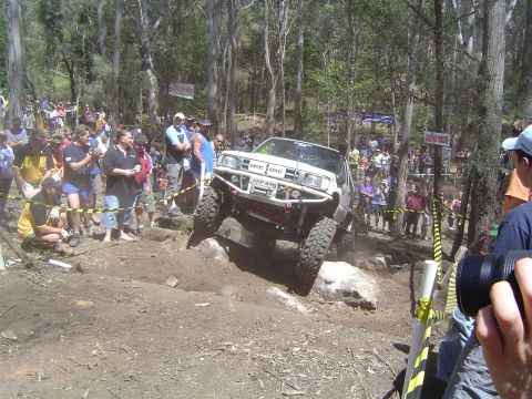 1982 Ford Bronco - An off-road vehicle navigates a challenging rocky terrain during an event, with spectators observing the action.