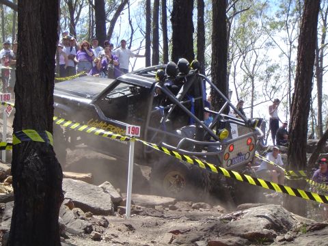 1982 Ford Bronco - Modified off-road buggy navigates a rocky course with spectators observing the action.