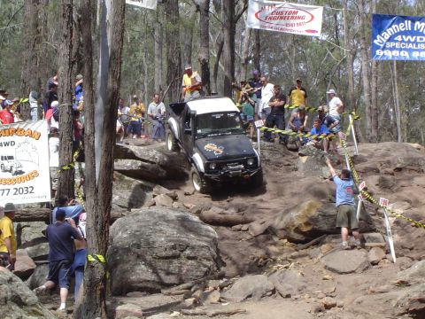 1982 Ford Bronco - An off-road competition features a vehicle tackling a challenging rocky course with onlookers.