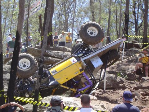 1982 Ford Bronco - An off-road vehicle has overturned on a rocky course, with onlookers observing the scene.