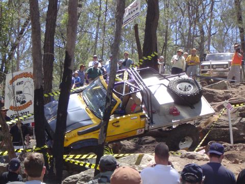 1982 Ford Bronco - A yellow off-road vehicle navigates a challenging rocky terrain during an event.