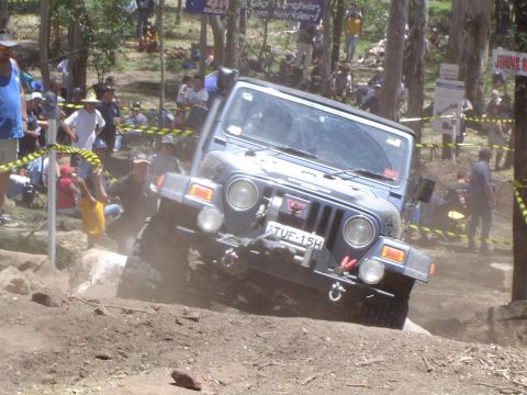 1982 Ford Bronco - A Jeep Wrangler TJ tackles a challenging off-road course with spectators watching.