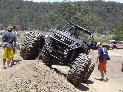 1982 Ford Bronco - This heavily modified off-road vehicle tackles a steep dirt incline with its enormous tires.