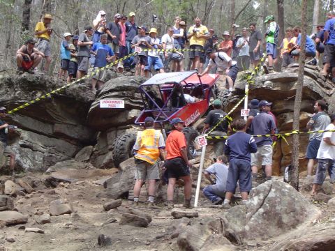 1982 Ford Bronco - A crowd watches an off-road buggy attempt a challenging rocky terrain during an event.