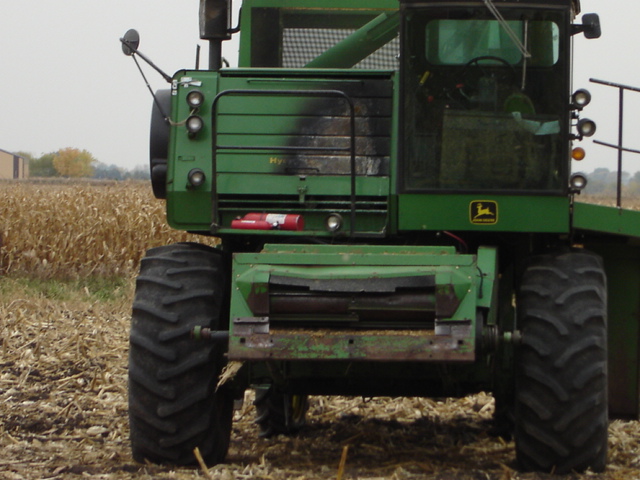 Green combine harvester with large tires in a harvested cornfield