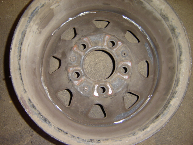 Close-up of a rusty metal wheel rim with visible lug nut holes