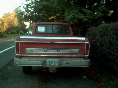 1978 Ford Bronco - Rear view of a red Ford pickup truck parked roadside with trees in the background.