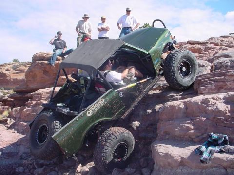 1988 Ford Bronco - An off-road vehicle navigates a rocky incline with several onlookers observing the challenging climb.