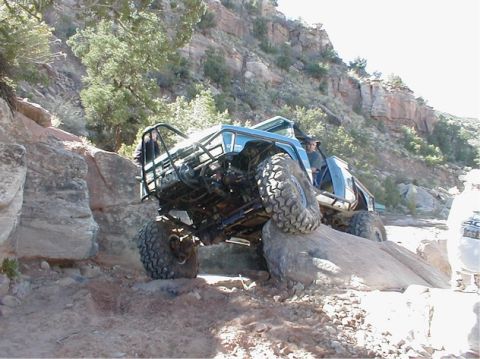 1988 Ford Bronco - A heavily modified off-road vehicle navigates a challenging rocky terrain.
