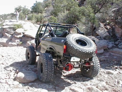 1988 Ford Bronco - Off-road SUV with extensive modifications navigates a rocky trail.