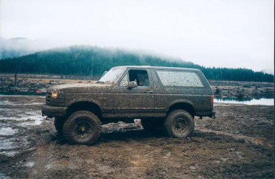 Mud-covered 1993 Ford Bronco side view in a muddy field