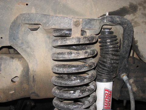1988 Ford Bronco - The front suspension system of a vehicle, a coil spring and shock absorber, is shown in this close-up.