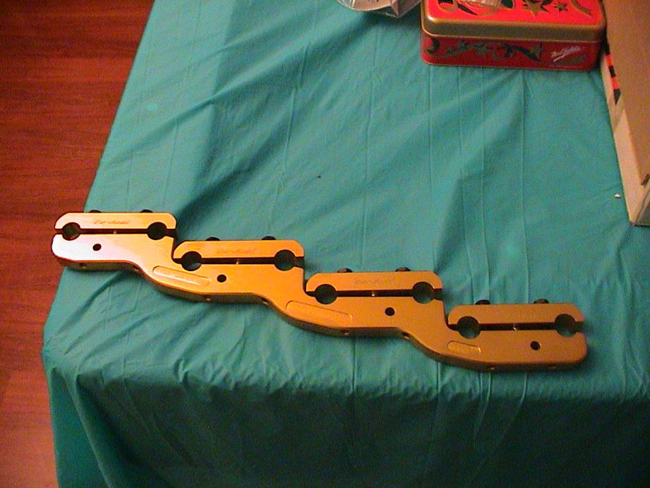 Gold-colored engine part with four clamps on a teal cloth