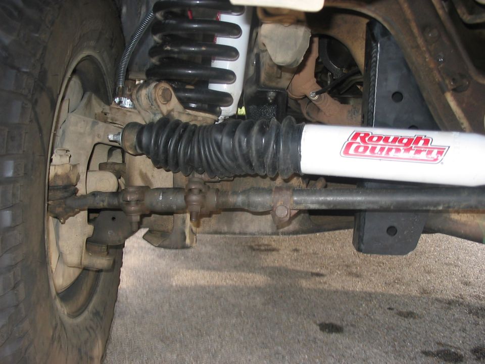 Close-up of vehicle steering linkage and Rough Country shock absorber