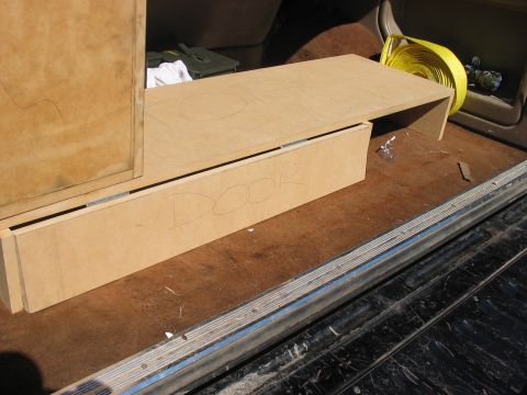 1988 Ford Bronco - Custom wooden storage box with 'DOOR' written on the side, situated in the rear of a vehicle.