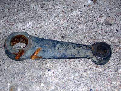 1995 Ford Bronco - A rusty steering linkage arm with "FMR-3TC" stamped on its side rests on a concrete surface.