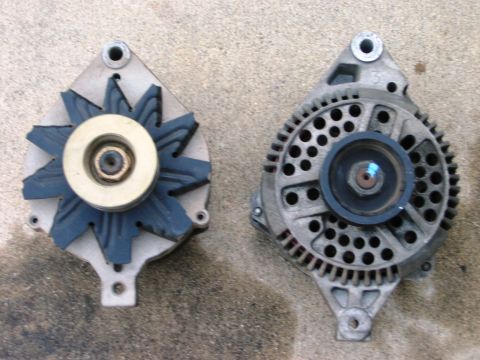 1985 Ford Bronco - Two automotive alternators are displayed side-by-side on a concrete surface, showing different designs and components.