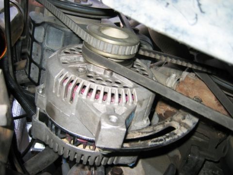 1985 Ford Bronco - Close-up view of an alternator and its associated drive belts within an engine compartment.