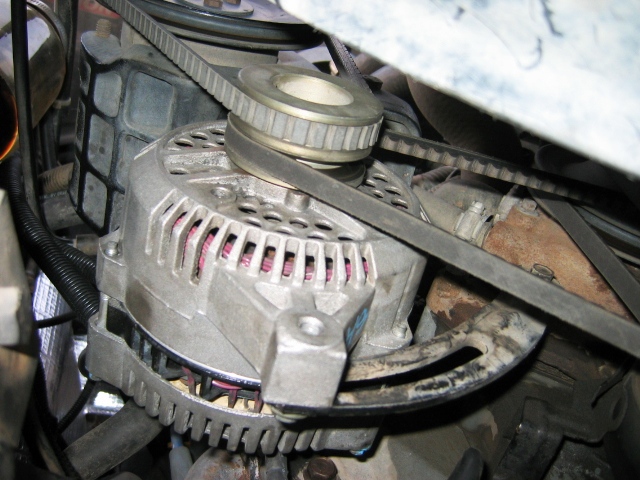 Alternator with serpentine belt and pulley in a grimy engine bay