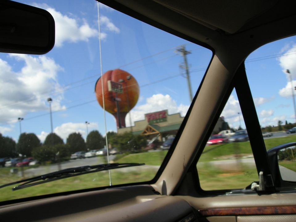 View through vehicle windshield of giant peach water tower and Fatz restaurant, tan dash and A-pillar visible