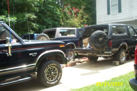 1979 Ford F-150 - Multiple Ford Broncos are parked outside a house, with one undergoing some work.