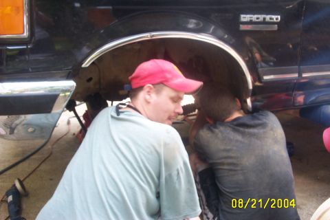 1979 Ford F-150 - Two men work on the suspension of a black Ford Bronco, with a date stamp of 08/21/2004 visible.
