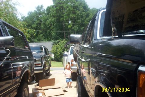 1979 Ford F-150 - Several Ford trucks are parked outside, including a 1979 Ford F-150, with a young child standing nearby.