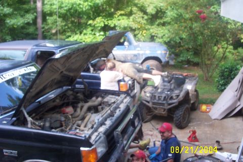 1979 Ford F-150 - Multiple vehicles, including trucks and an ATV, are undergoing maintenance outdoors on a summer day in 2004.