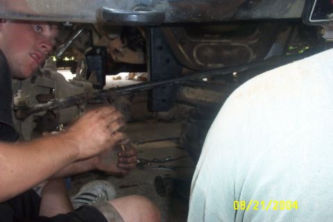 1979 Ford F-150 - Mechanics are seen working on the underside of a vehicle, likely performing repairs or modifications.