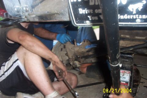 1979 Ford F-150 - Mechanics are working on the drivetrain of a vehicle that is supported by a jack.