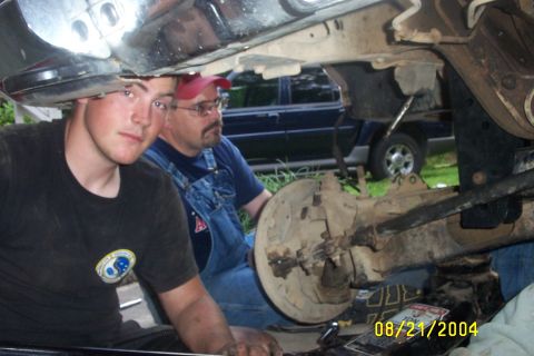 1979 Ford F-150 - Two individuals are seen working on the undercarriage of a vehicle, with a date stamp indicating August 21, 2004.