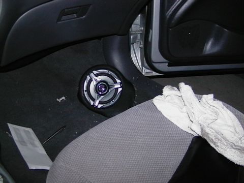 1999 Ford Taurus - Aftermarket speaker installed in the footwell of a car's interior. A cloth lies on the passenger seat.