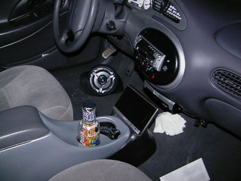 1999 Ford Taurus - The interior of a car shows aftermarket modifications and a bottle of air freshener in the cup holder.