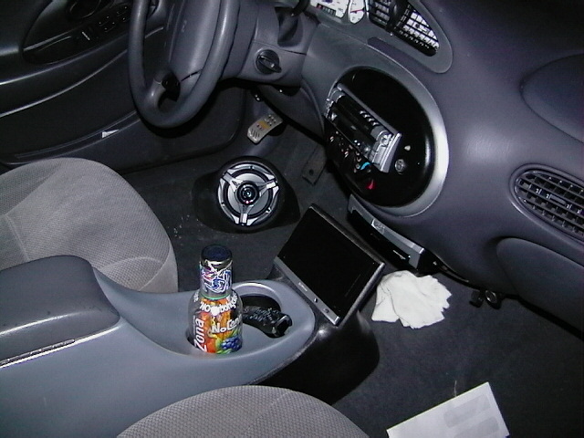 Car interior with gray seats, aftermarket stereo, and a bottle of air freshener in the center console