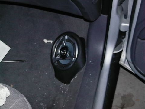 1999 Ford Taurus - A car interior shot showing a speaker installed on the floor near the door.