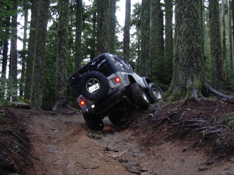 1991 Ford Bronco - A Jeep Wrangler navigates a challenging, rocky incline on a forest trail.